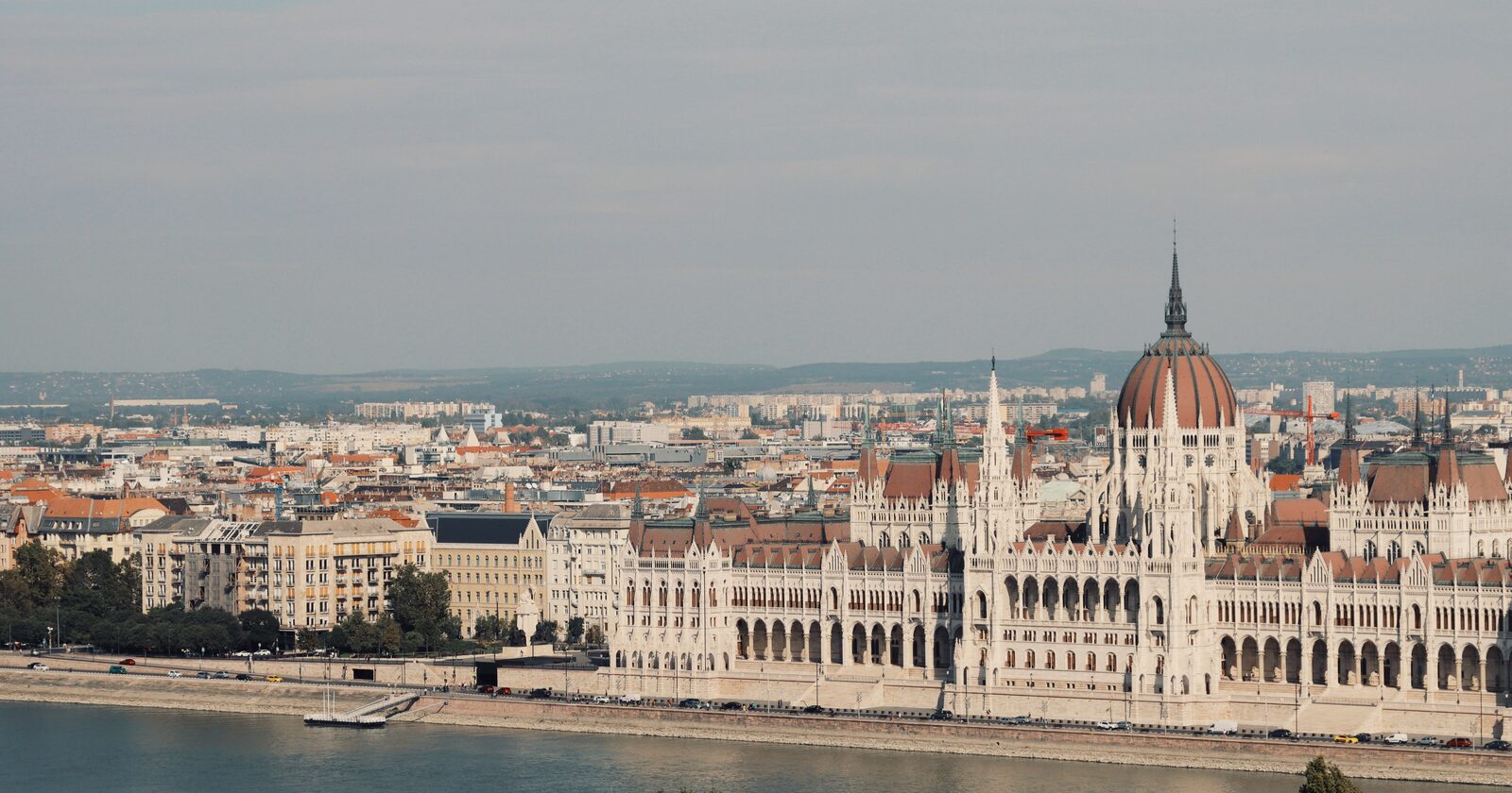 The Hungarian Parliament Building on the Danube riverbank in Budapest, with the city skyline behind